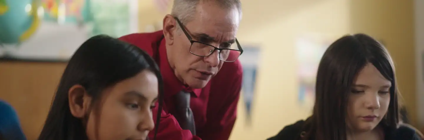Teacher and his students looking at a Chromebook